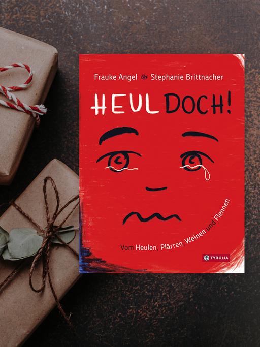 Cover vom Buch „Heul doch. Vom Heulen, Plärren, Weinen und Flennen“ von  Frauke Angel und Stephanie Brittnacher:
Tyrolia Verlag/ Innsbruck 2021. Im Hintergrund sind graue Päckchen mit rot-weißen Schleifen zu sehen. 