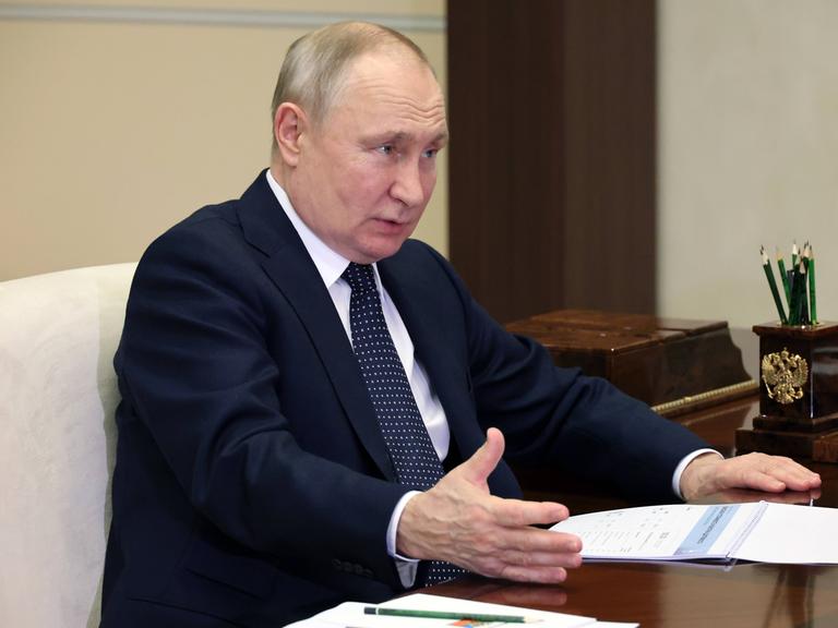 Der russische Präsident Wladimir Putin sitzt an einem Tisch und gestikuliert.