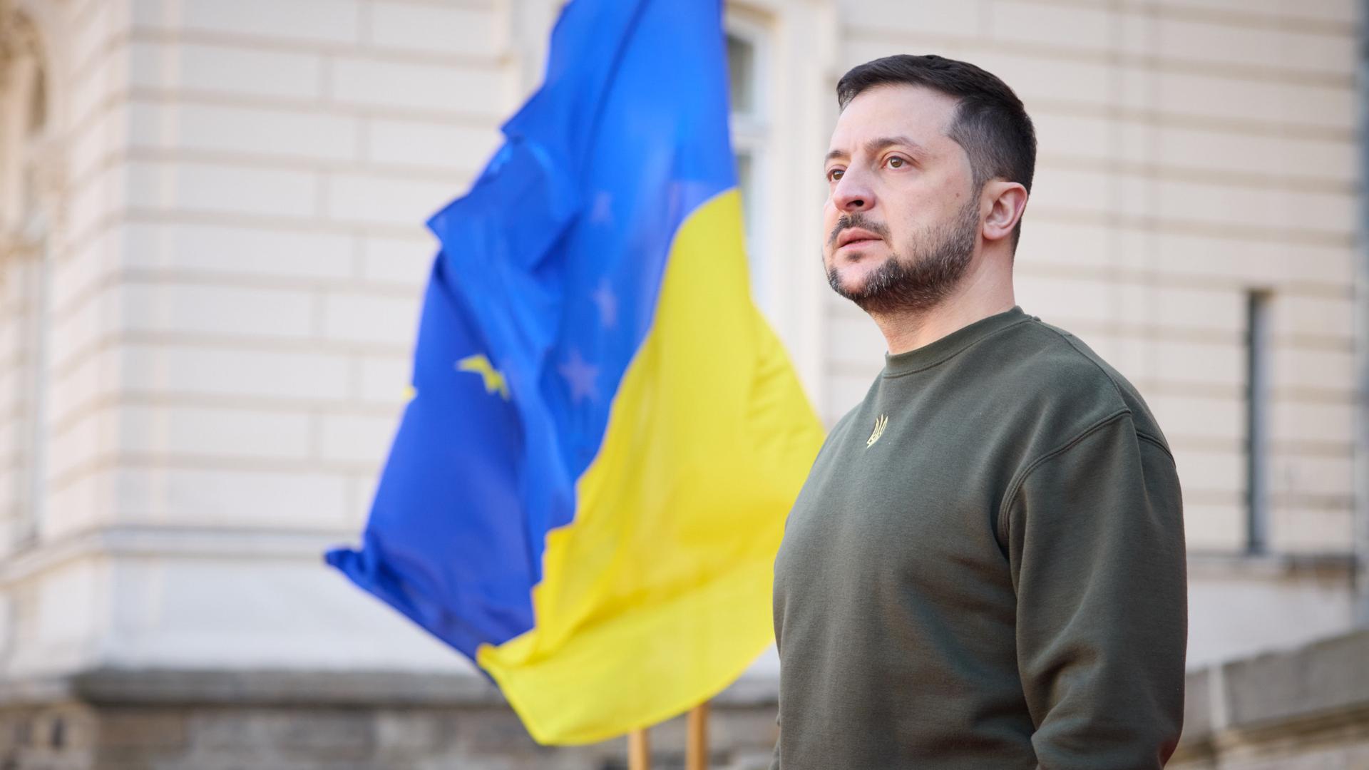 Der ukrainische Präsident Wolodymyr Selenskyj steht vor einem Gebäude, neben ihm weht eine ukrainische Flagge Der ukrainische Präsident Wolodymyr Selenskyj steht vor einem Gebäude, neben ihm weht eine ukrainische Flagge