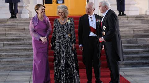 König Charles III. und seine Frau Camilla sowie Bundespräsident Steinmeier und seine Frau stehen vor dem Eingang des Schlosses Bellevue. Alle sind festlich gekleidet; die Frauen in Abendkleidern, die Herren im Frack.