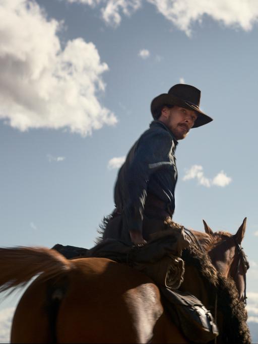 Filmszene aus dem Western "The Power of the Dog". Zu sehen ist der Hauptdarsteller Benedict Cumberbatch auf einem Pferd sitzend.