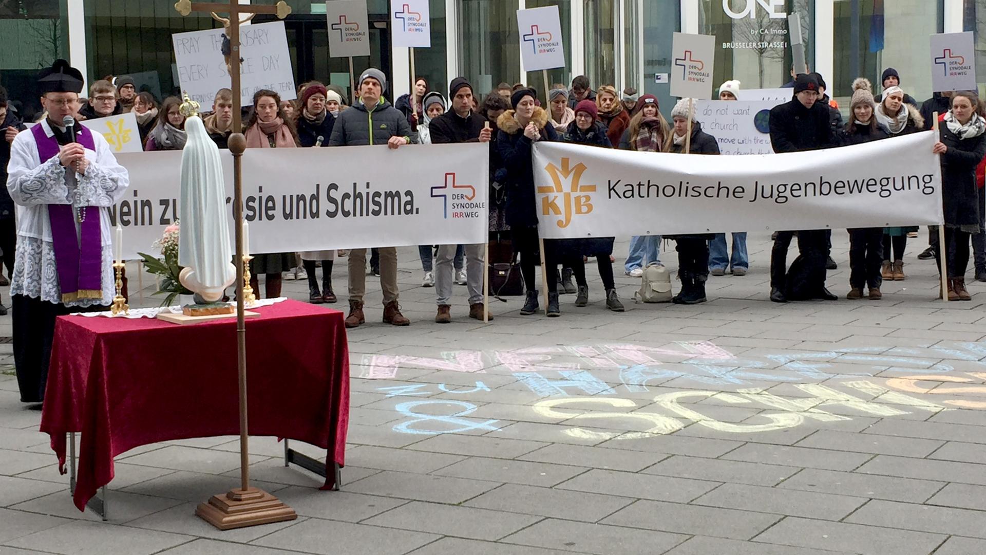 Reformgegner demonstrieren zum Abschluss der fünften Synodalversammlung zur Erneuerung der katholischen Kirche vor dem Veranstaltungsgebäude gegen die Beschlüsse. Unter dem Motto "Nein zu Häresie und Schisma" forderte eine kleine Gruppe von Protestierenden den Rücktritt des Vorsitzenden der Deutschen Bischofskonferenz. Auf dem Foto ist ein Priester mit einem Birett zu sehen. Er betet vor einer Mar Reformgegner demonstrieren zum Abschluss der fünften Synodalversammlung zur Erneuerung der katholischen Kirche vor dem Veranstaltungsgebäude gegen die Beschlüsse. Unter dem Motto "Nein zu Häresie und Schisma" forderte eine kleine Gruppe von Protestierenden den Rücktritt des Vorsitzenden der Deutschen Bischofskonferenz. Auf dem Foto ist ein Priester mit einem Birett zu sehen. Er betet vor einer Mar