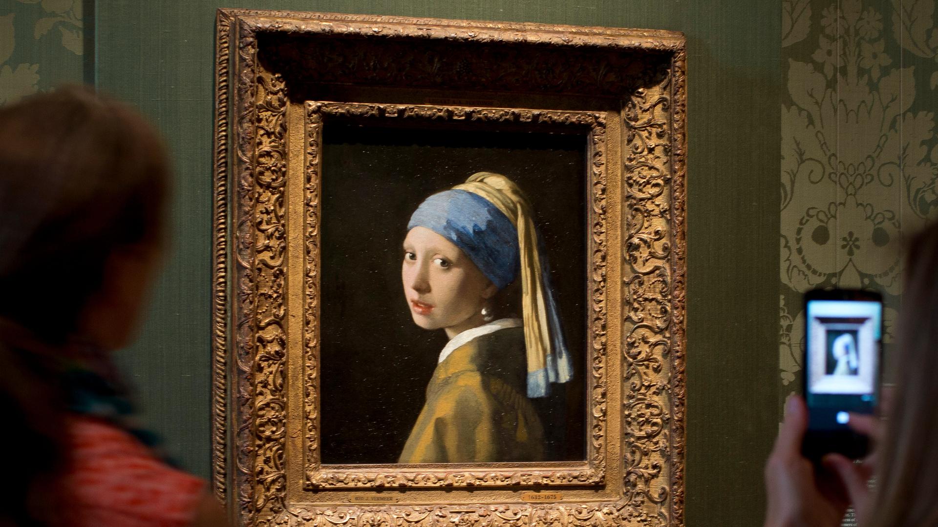 Besucher fotografieren das Bild "Mädchen mit dem Perlen-Ohr-Ring" von dem Maler Johannes Vermeers. Besucher fotografieren das Bild "Mädchen mit dem Perlen-Ohr-Ring" von dem Maler Johannes Vermeers.