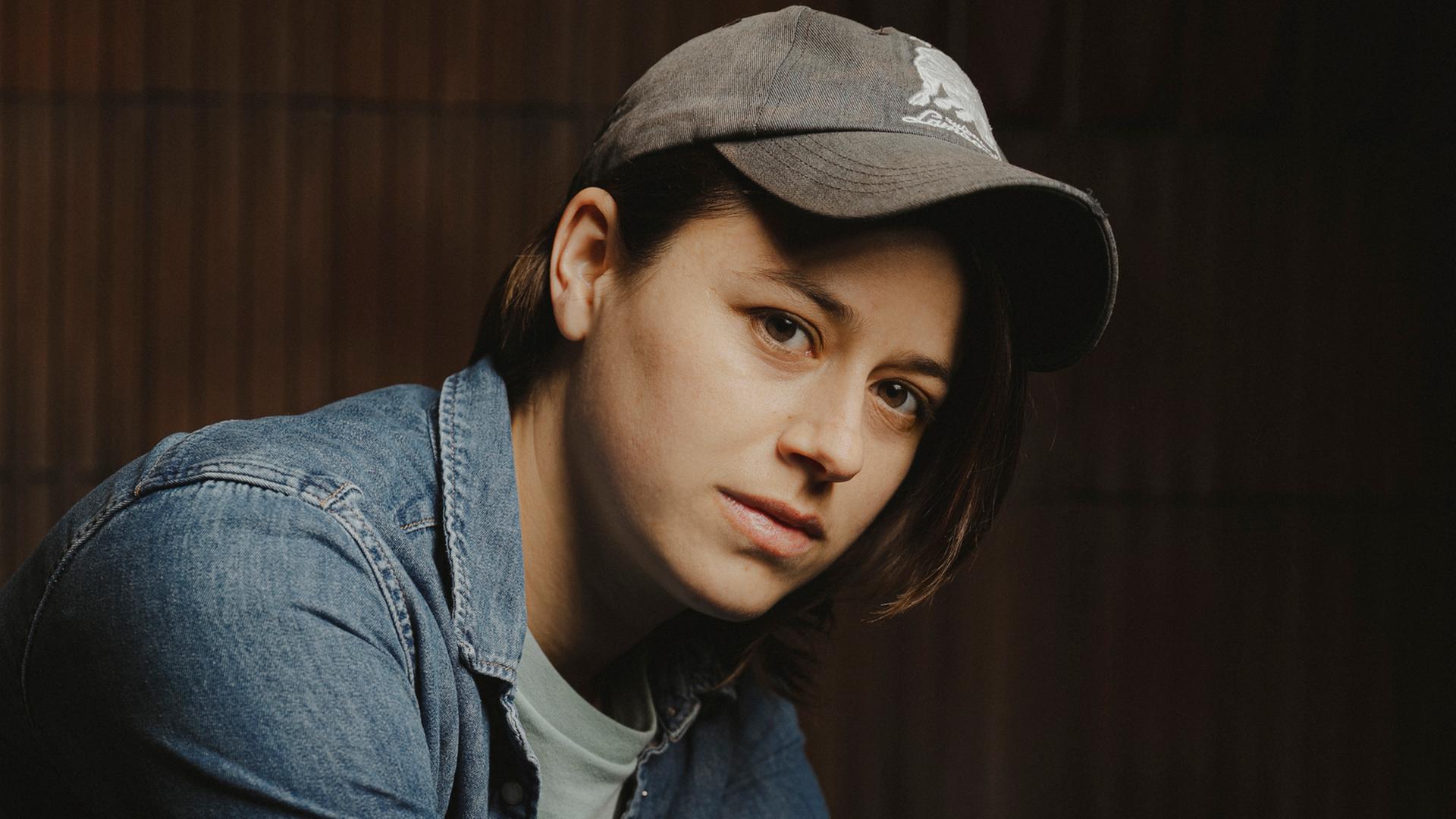 Die Schweizer Autorin Sarah Elena Müller. Sie posiert mit Basecap und in Jeanshemd und weißem T-Shirt vor der Kamera. Die Schweizer Autorin Sarah Elena Müller. Sie posiert mit Basecap und in Jeanshemd und weißem T-Shirt vor der Kamera.