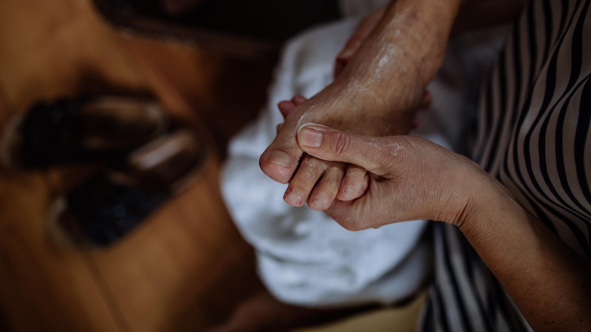 Die Hand einer jungen Person berührt den Fuss einer alten Person. Die Hand einer jungen Person berührt den Fuss einer alten Person.