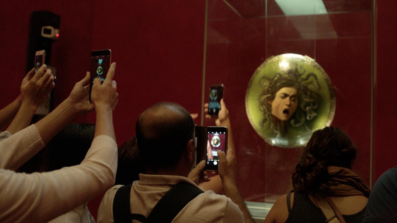 Besucher mit gezückten Smartphones fotografieren ein Gemäde der Medusa. Besucher mit gezückten Smartphones fotografieren ein Gemäde der Medusa.