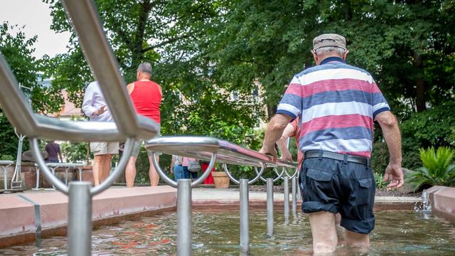 Menschen kühlen sich am 13.07.22 beim Wassertreten in einem Kneipp-Becken im Kurgarten von Bad Kissingen ab. 