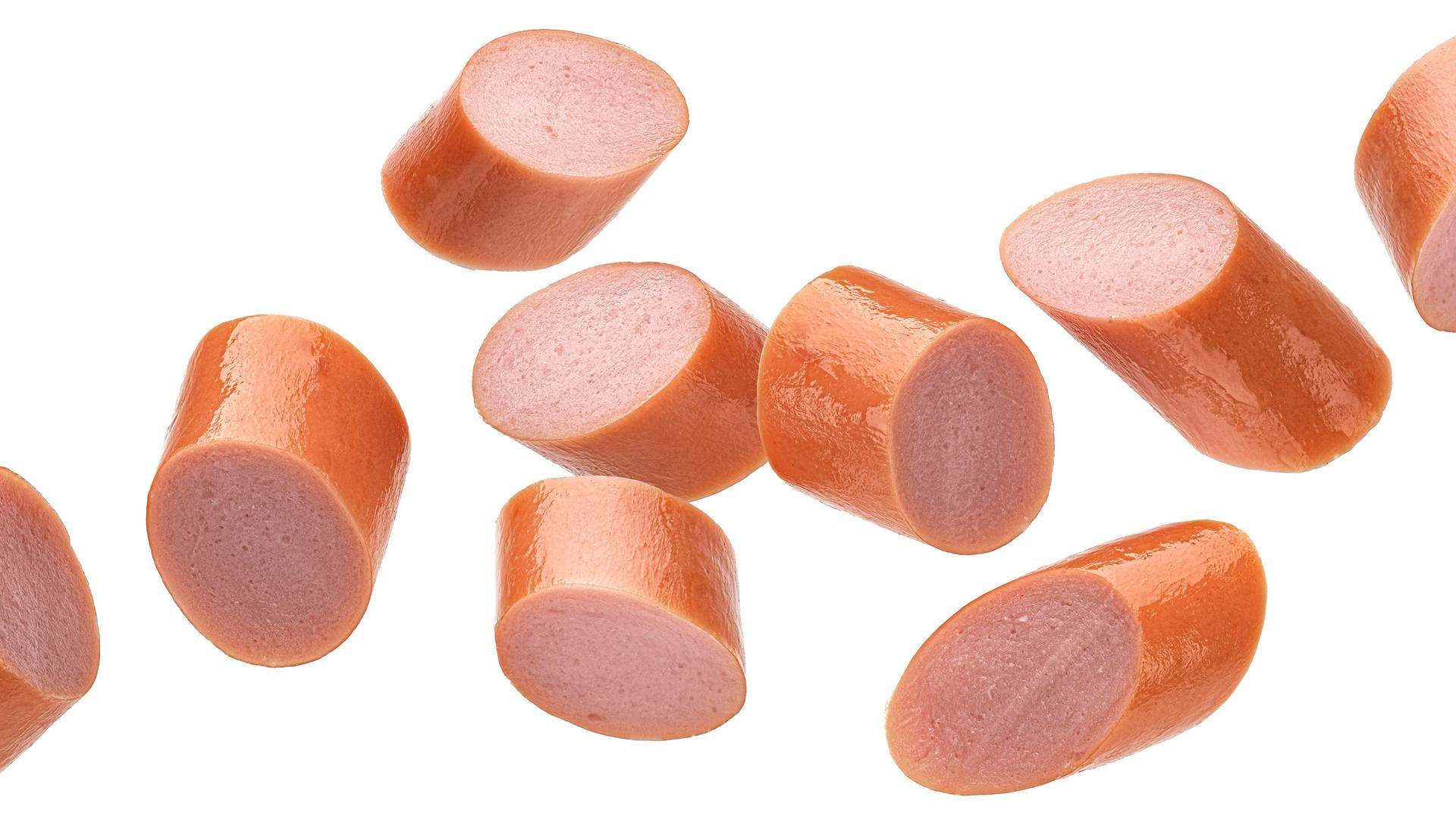 Eine in Stücke geschnittene Wiener Wurst vor weißem Hintergrund Eine in Stücke geschnittene Wiener Wurst vor weißem Hintergrund