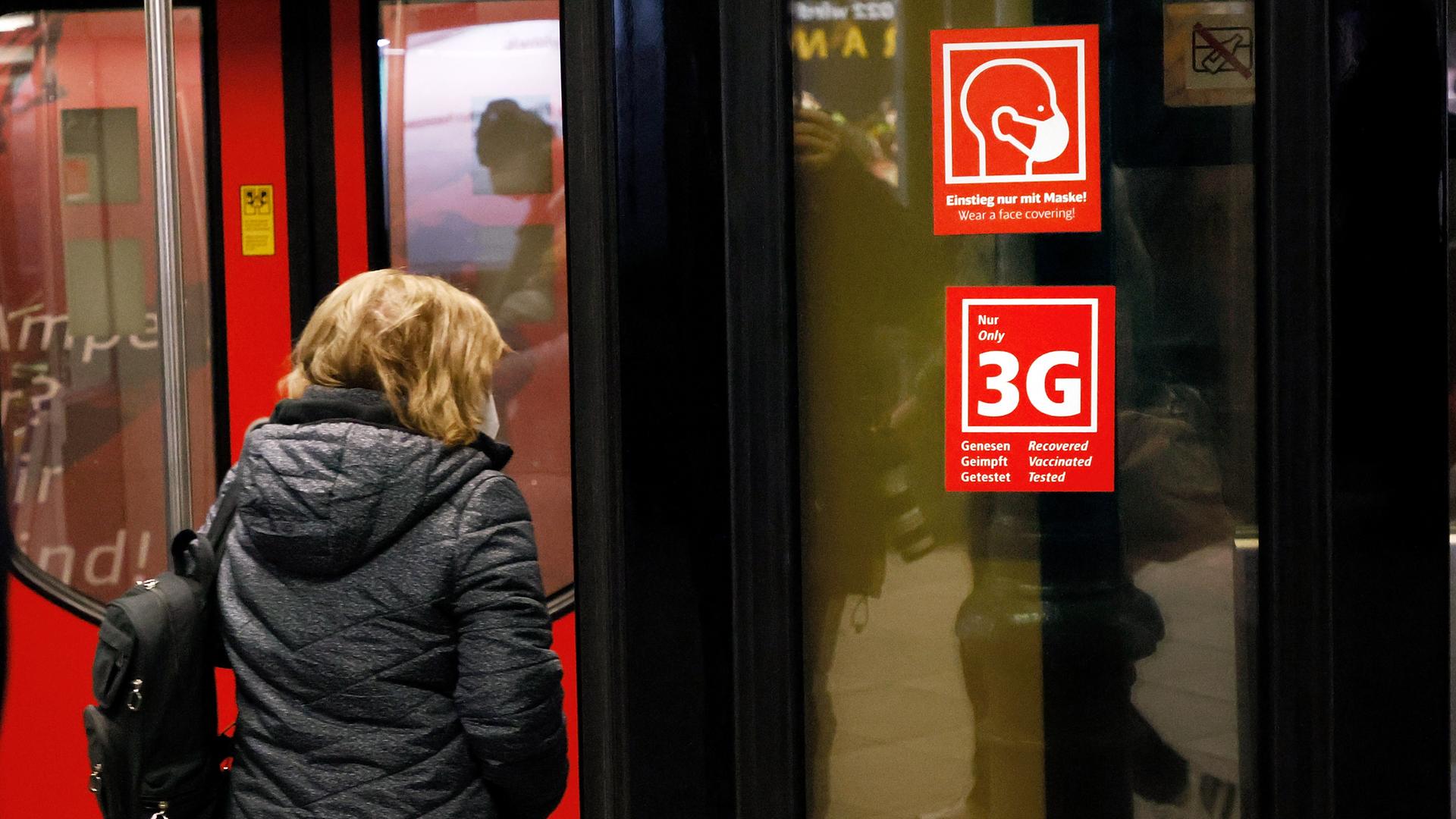 Ein Fahrgast betritt eine Bahn, an der Schilder mit dem Hinweis auf die Maskenpflicht und und die 3G-Regel zu sehen sind. Ein Fahrgast betritt eine Bahn, an der Schilder mit dem Hinweis auf die Maskenpflicht und und die 3G-Regel zu sehen sind.