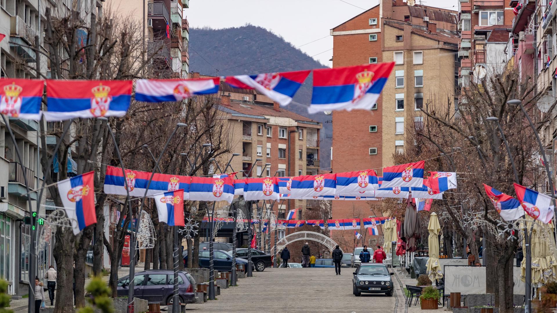 MITROVICA, KOSOVO - DECEMBER 28: A view of King Peter One road with multiple Serbian flags hanged on wires near the Mitrovica Bridge over the Ibar River in Northern Mitrovica, Kosovo as tension between Kosovo and Serbia continue on December 28, 2022. Tensions between Kosovo and Serbia have escalated since the detention of former Serbian police officer Dejan Pantic on suspicion of attacking electio MITROVICA, KOSOVO - DECEMBER 28: A view of King Peter One road with multiple Serbian flags hanged on wires near the Mitrovica Bridge over the Ibar River in Northern Mitrovica, Kosovo as tension between Kosovo and Serbia continue on December 28, 2022. Tensions between Kosovo and Serbia have escalated since the detention of former Serbian police officer Dejan Pantic on suspicion of attacking electio