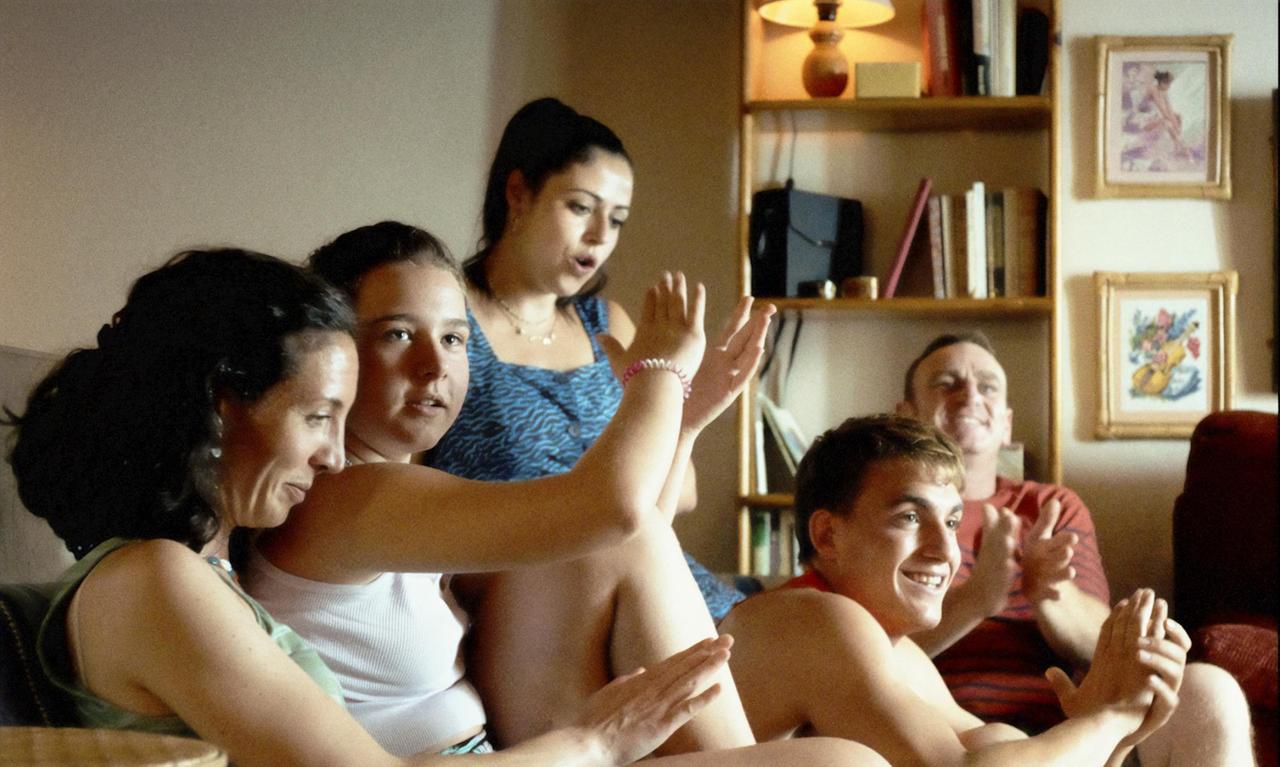 Eine Familie sitzt im Wohnzimmer lachend beeinander. Eine Familie sitzt im Wohnzimmer lachend beeinander.