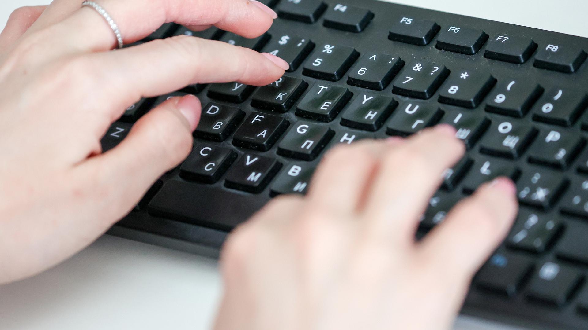 Hände tippen auf einer Computertastatur mit kyrillischen Buchstaben. Hände tippen auf einer Computertastatur mit kyrillischen Buchstaben.
