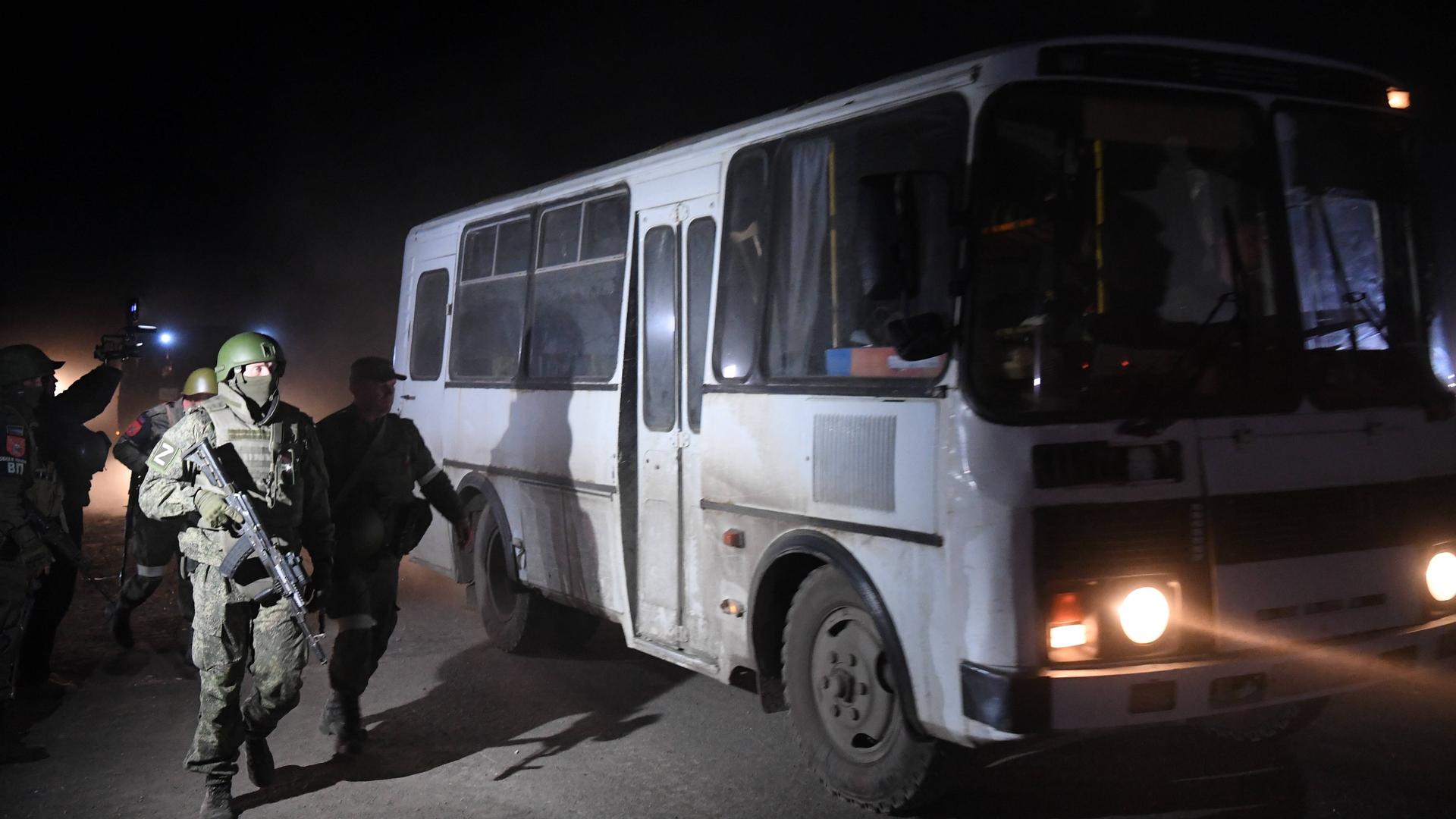 Bewaffnete Soldaten stehen vor einem Bus