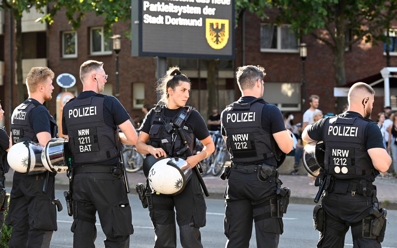 Fünf Polizisten einer Hundertschaft stehen mit abgezogenen Helmen auf einer Straße in Dortmund