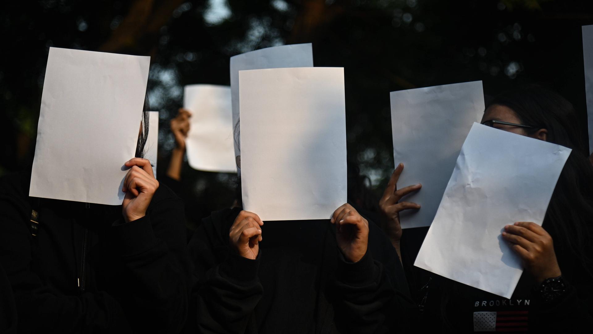 Tibetische Aktivisten halten am 02.12.2022 in New Delhi aus Solidarität mit den Whitepaper Protests in China leere Blätter in die Höhe.