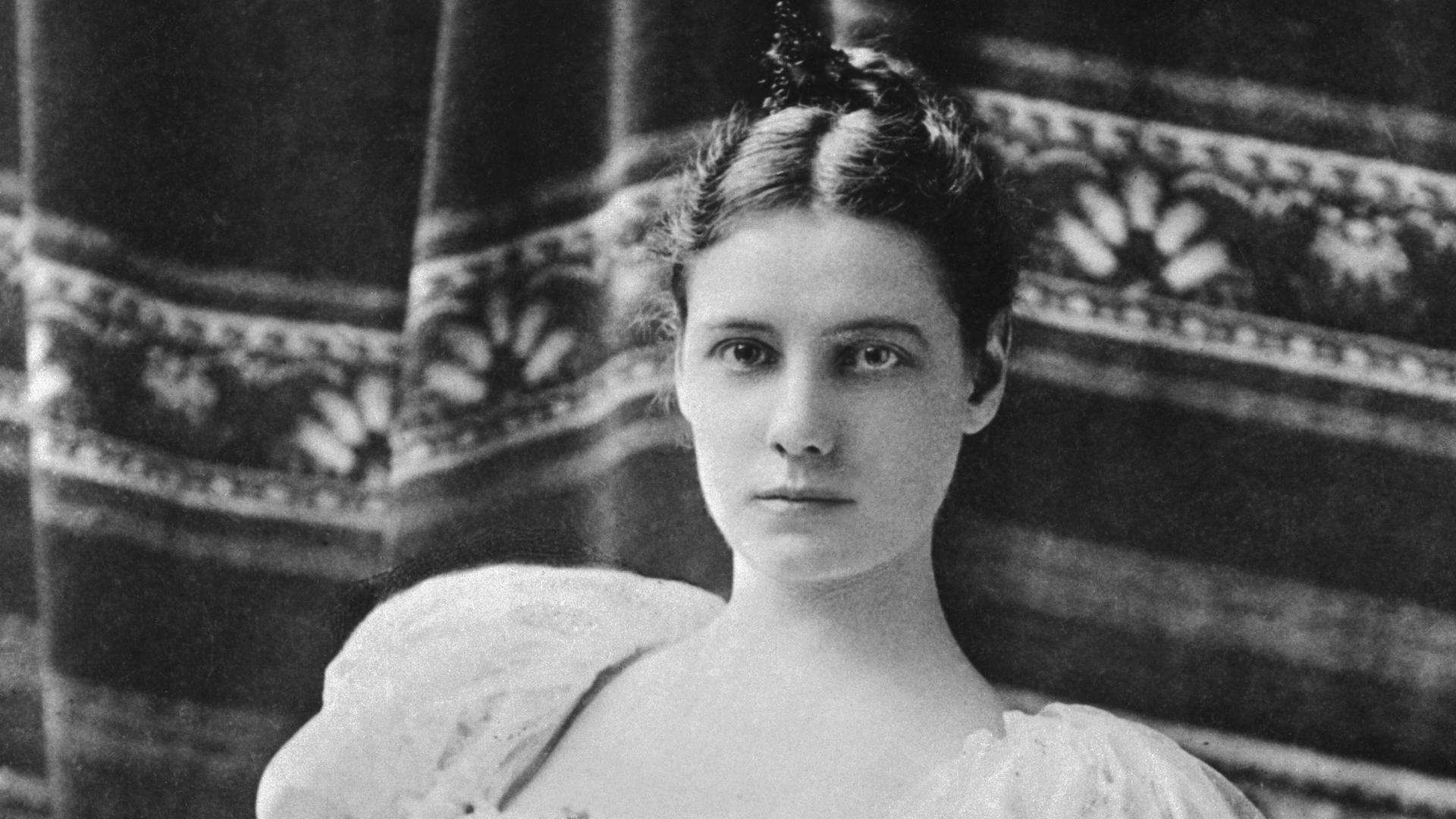 Eine historische Schwarz-weiß-Aufnahme zeigt die Autorin Nellie Bly in einem zeittypischen Kleid mit viel Spize und Rüschen (1864 -1922). Eine historische Schwarz-weiß-Aufnahme zeigt die Autorin Nellie Bly in einem zeittypischen Kleid mit viel Spize und Rüschen (1864 -1922).