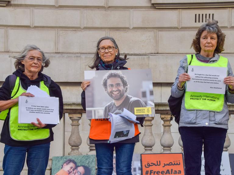 Demonstranten halten beschriebene Blätter und ein Bild des Ägypters Alaa Abdel Fattah in den Händen.