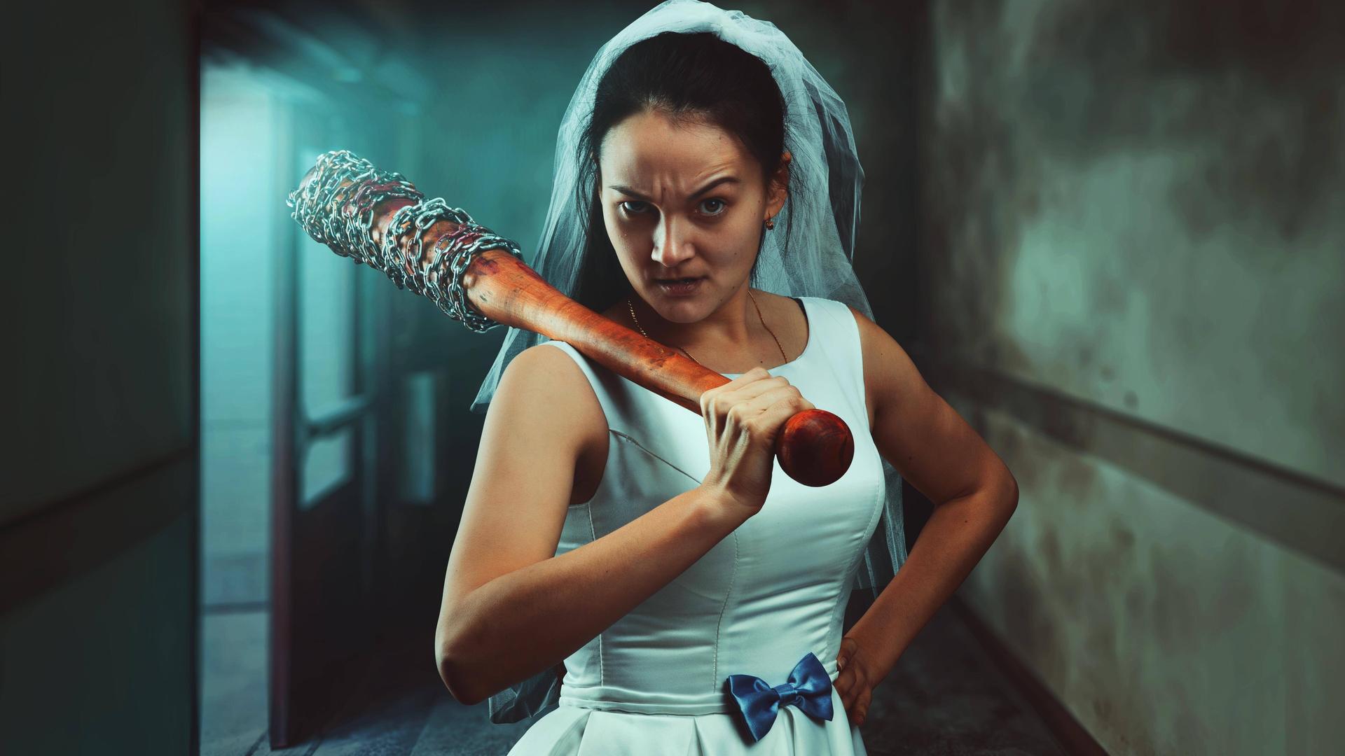 Eine Braut in weißem Hochzeitskleid mit Baseballschläger. Eine Braut in weißem Hochzeitskleid mit Baseballschläger.