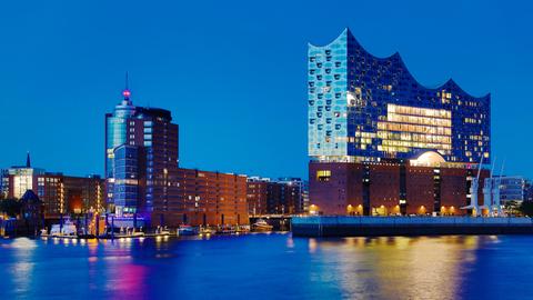Ein blauer, wolkenloser Himmel wie man ihn abends beobachten kann, wenn die Sonne schon tief gesunken ist, aber der Himmel trotzdem noch eine restliche Helligkeit hat. Das Panorama zeigt die Umrisse der Elbphilharmonie in Hamburg.