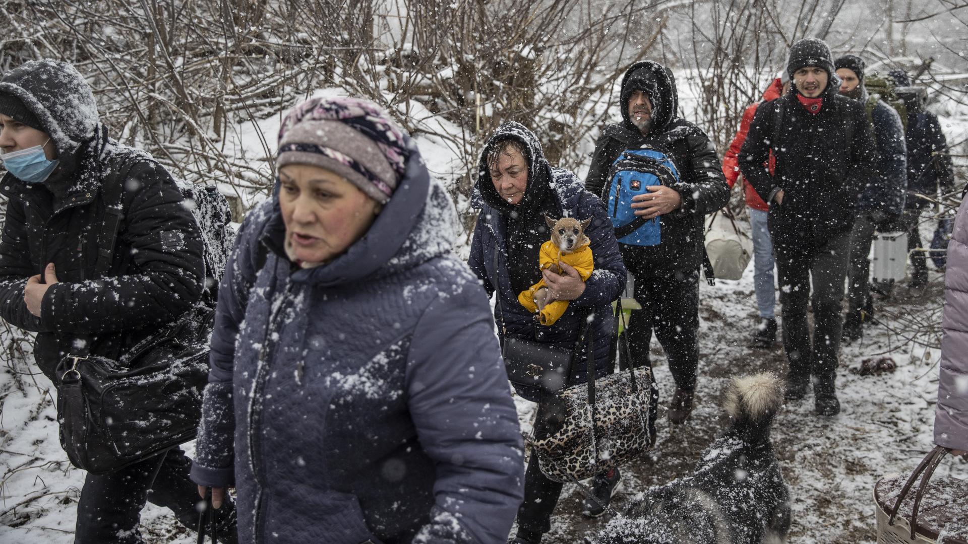 Zivilisten fliehen durch den Schneefall aus der umkämpften Stadt Irpin in der Ukraine. Zivilisten fliehen durch den Schneefall aus der umkämpften Stadt Irpin in der Ukraine.