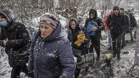 Zivilisten fliehen durch den Schneefall aus der umkämpften Stadt Irpin in der Ukraine. 