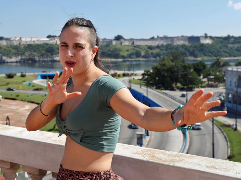 Cristina Morales gestikuliert fröhlich auf einem Balkon.