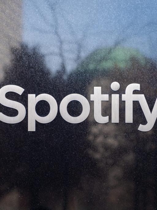 Das Logo des Musikstreaming-Dienstes Spotify klebt auf einer Scheibe.