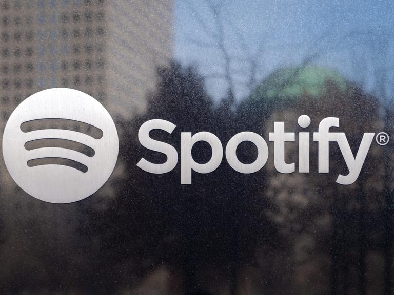 Das Logo des Musikstreaming-Dienstes Spotify klebt auf einer Scheibe.