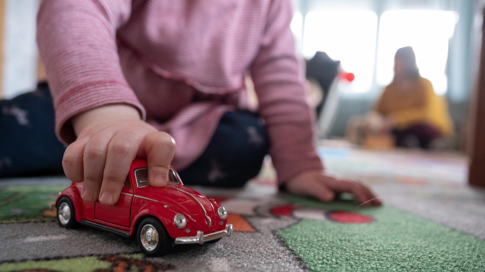 Ein Kind spielt zu Hause mit einem roten Spielzeugauto. Ein Kind spielt zu Hause mit einem roten Spielzeugauto.