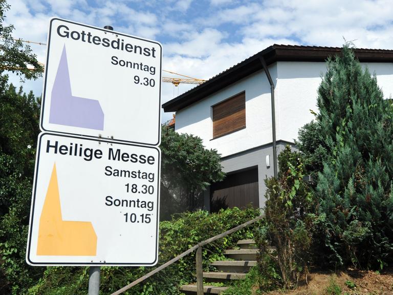 An einem Haus in Leutkirch (Kreis Ravensburg) sind die Rollläden heruntergelassen. Vor dem Haus zwei Schilder mit Hinweise auf den Gottesdienst und die Heilige Messe