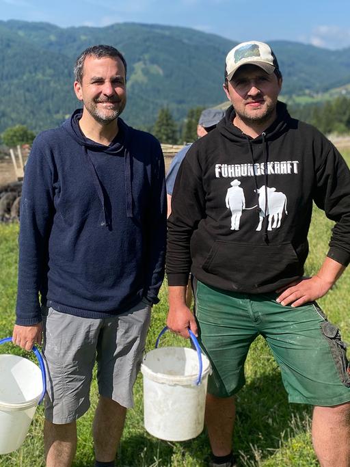 Florian Klenk und Christian Bachler mit Eimern auf einer Weide.