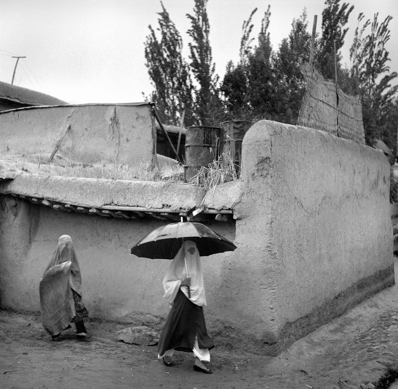 Afghanische Frauen mit einem Regenschirm, auf dem Weg zum Markt. Sie tragen Vollverschleierung, eine Burka. Badakhshan Provinz, 2001. Afghanische Frauen mit einem Regenschirm, auf dem Weg zum Markt. Sie tragen Vollverschleierung, eine Burka. Badakhshan Provinz, 2001.