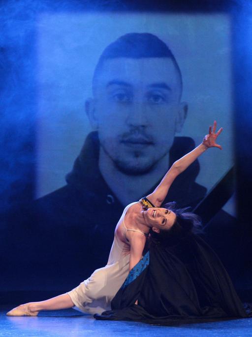 Eine Tänzerin tanzt auf einer ganz in blau gehaltenen Bühne vor dem Bildnis eines Soldaten im Kiewer Nationaltheater. 