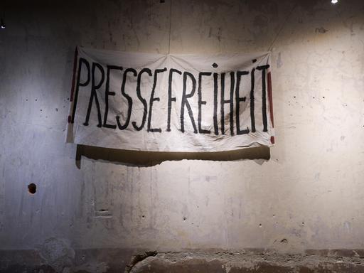 Ein Transparent mit der Aufschrift "Pressefreiheit" hängt vor einer unverputzten Wand. Es stammt aus den Dreharbeiten zum historischen ZDF-Dreiteiler "The Wall".