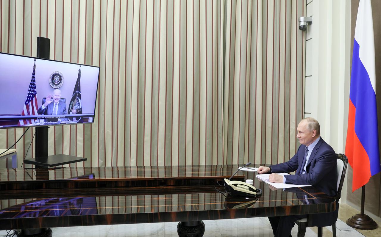 Der russische Präsident Wladimir Putin sitzt an einem Konferenztisch und schaut auf einen Bildschirm, auf dem der amerikanische Präsident Joe Biden zugeschaltet ist.