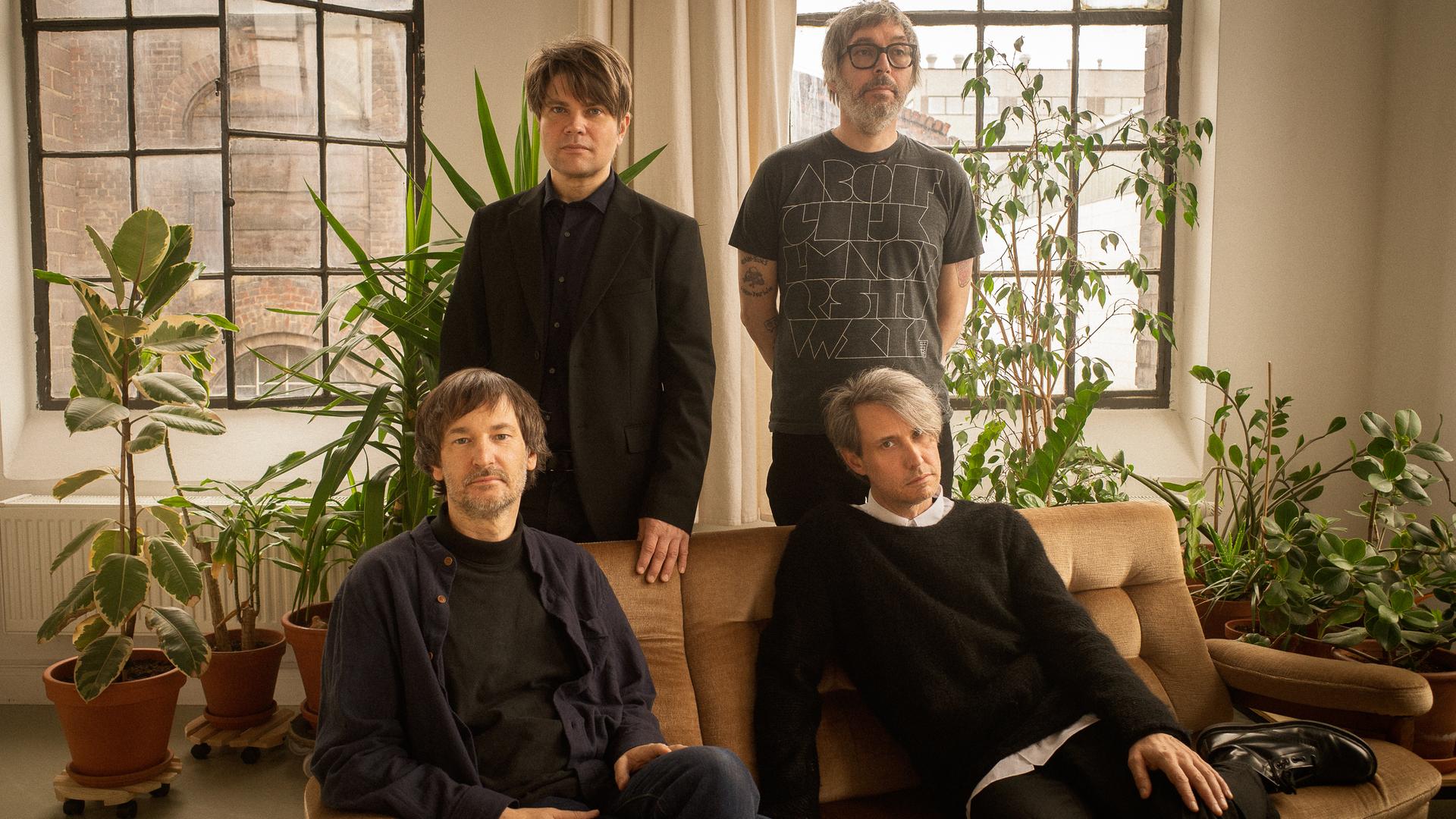 Die Mitglieder der Band Tocotronic: Dirk von Lowtzow und Arne Zank sitzen auf einem Sofa, Jan Müller und Rick McPhail stehen dahinter. Die Mitglieder der Band Tocotronic: Dirk von Lowtzow und Arne Zank sitzen auf einem Sofa, Jan Müller und Rick McPhail stehen dahinter.