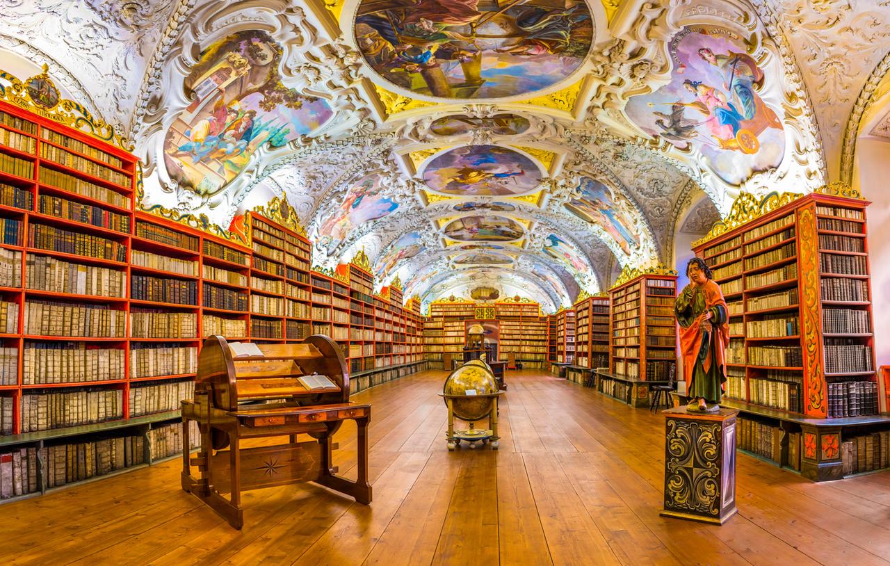 Historische Bibliothek in Prag mit Globen, alten Büchern und farbenfrohen Deckengemälden.