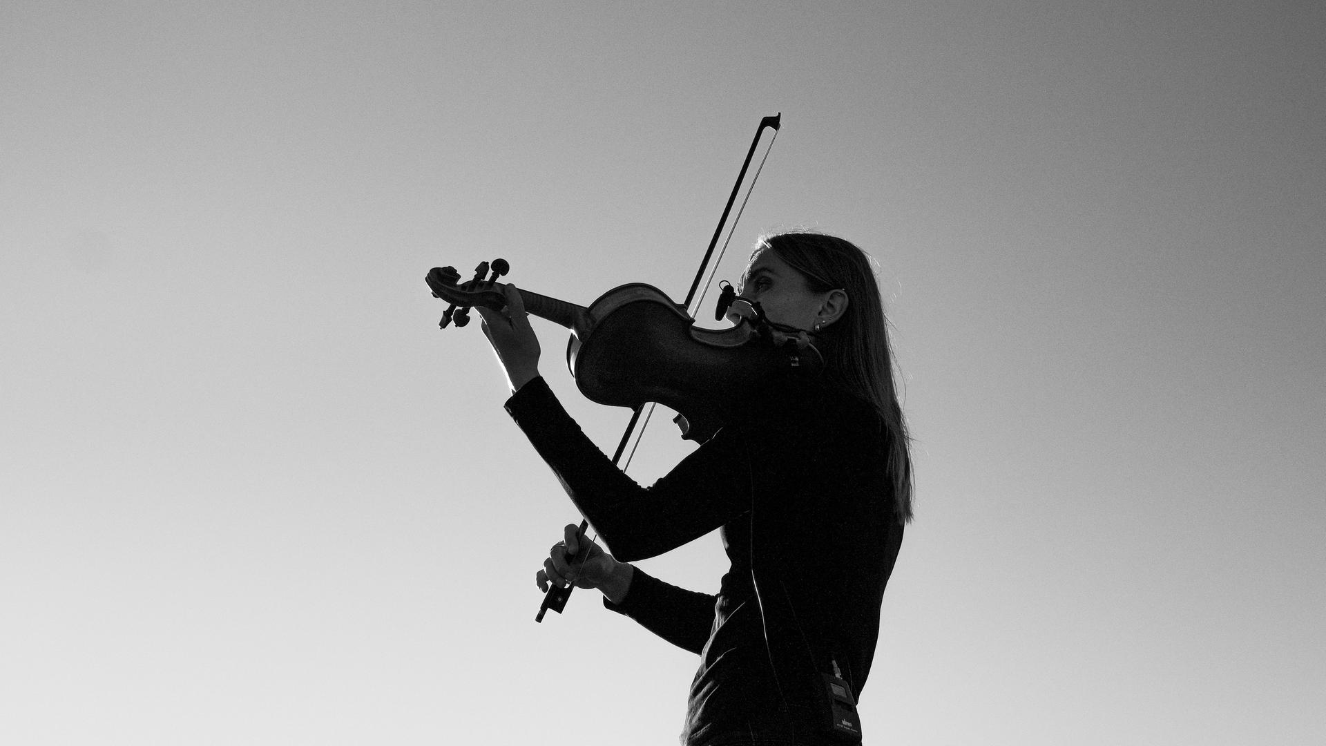 Ein Schwarz-Weiß-Foto zeigt eine Violinistin beim Musizieren. Ein Schwarz-Weiß-Foto zeigt eine Violinistin beim Musizieren.