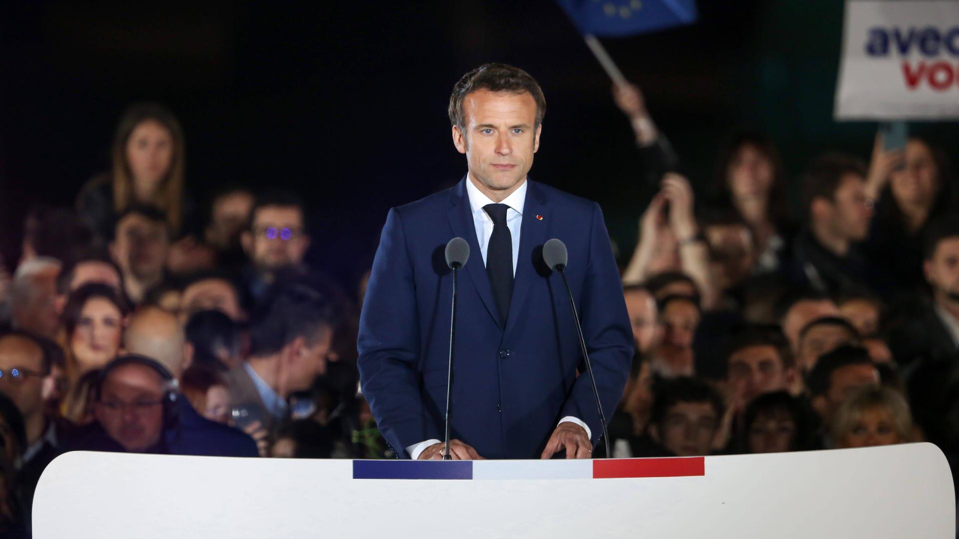 Emmanuel Macron steht an einem Rednerpult und schaut zum Publikum.