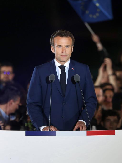 Emmanuel Macron steht an einem Rednerpult und schaut zum Publikum.