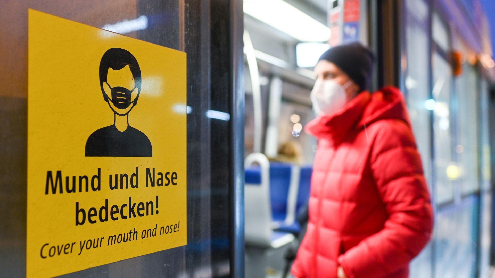 Eine Frau mit Maske steigt in eine Bahn ein. Eine Frau mit Maske steigt in eine Bahn ein.