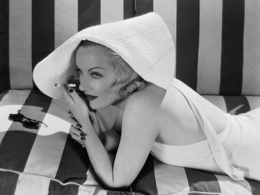 Die Hollywood Schauspielerin Carole Lombard, rauchend im Badeanzug, circa 1930.