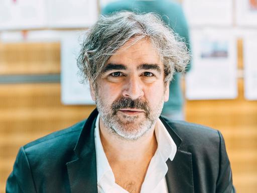 Der Journalist Deniz Yücel blickt in die Kamera. Er trägt ein dunkles Sakko und einen kurzen, graumelierten Bart.