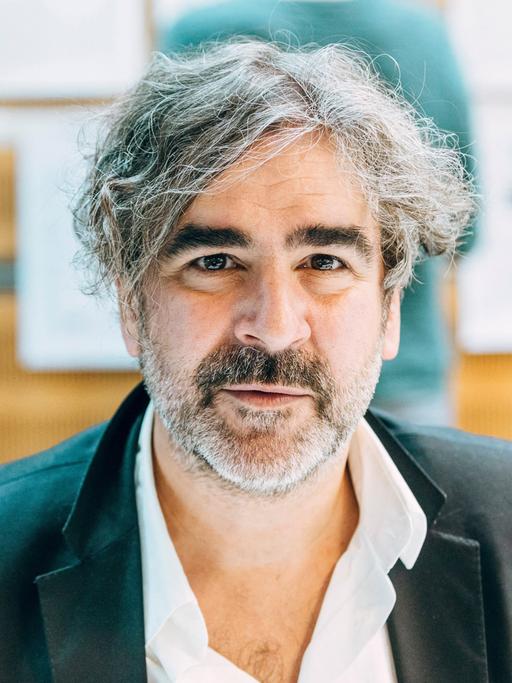 Der Journalist Deniz Yücel blickt in die Kamera. Er trägt ein dunkles Sakko und einen kurzen, graumelierten Bart.