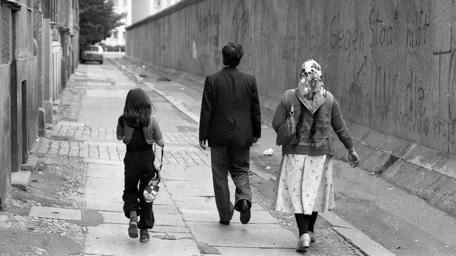 Eine türkische Familie geht entlang der Berliner Mauer spazieren. Eine türkische Familie geht entlang der Berliner Mauer spazieren.