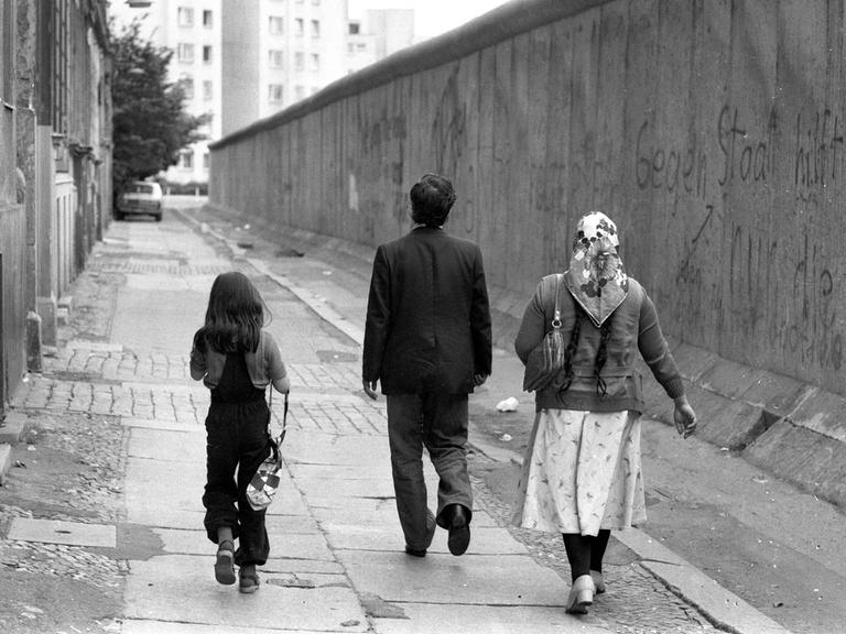 Eine türkische Familie geht entlang der Berliner Mauer spazieren.
