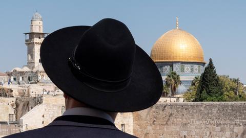 Ein orthodoxer Jude mit schwarzem Hut vor dem Felsendom in Jerusalem.
