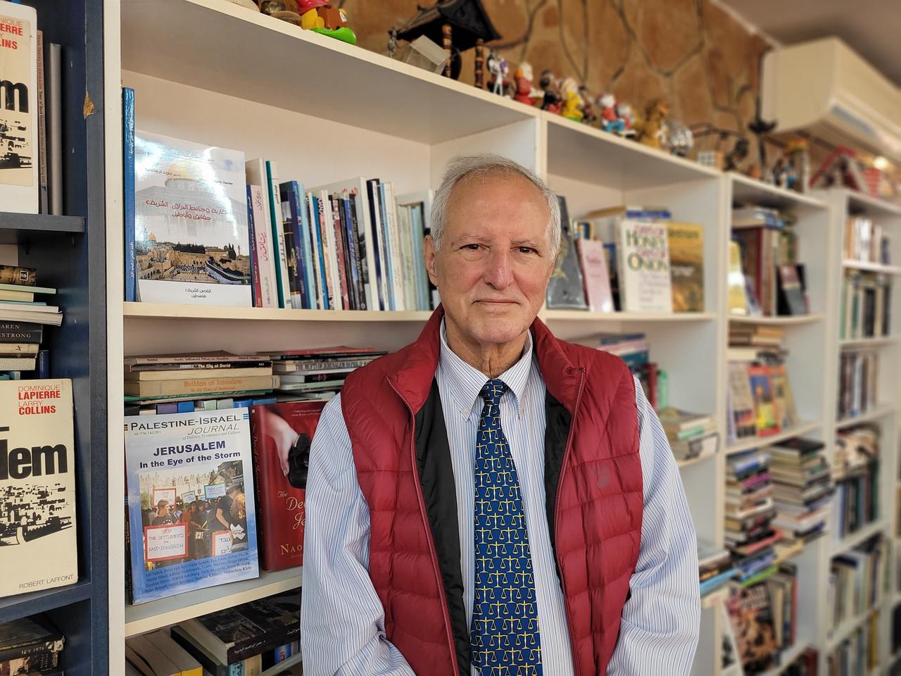 Ein Mann mit weißem Haar steht vor einem Bücherregal und schaut freundlich in die Kamera: der Professor Dajani Daoudi. Ein Mann mit weißem Haar steht vor einem Bücherregal und schaut freundlich in die Kamera: der Professor Dajani Daoudi.