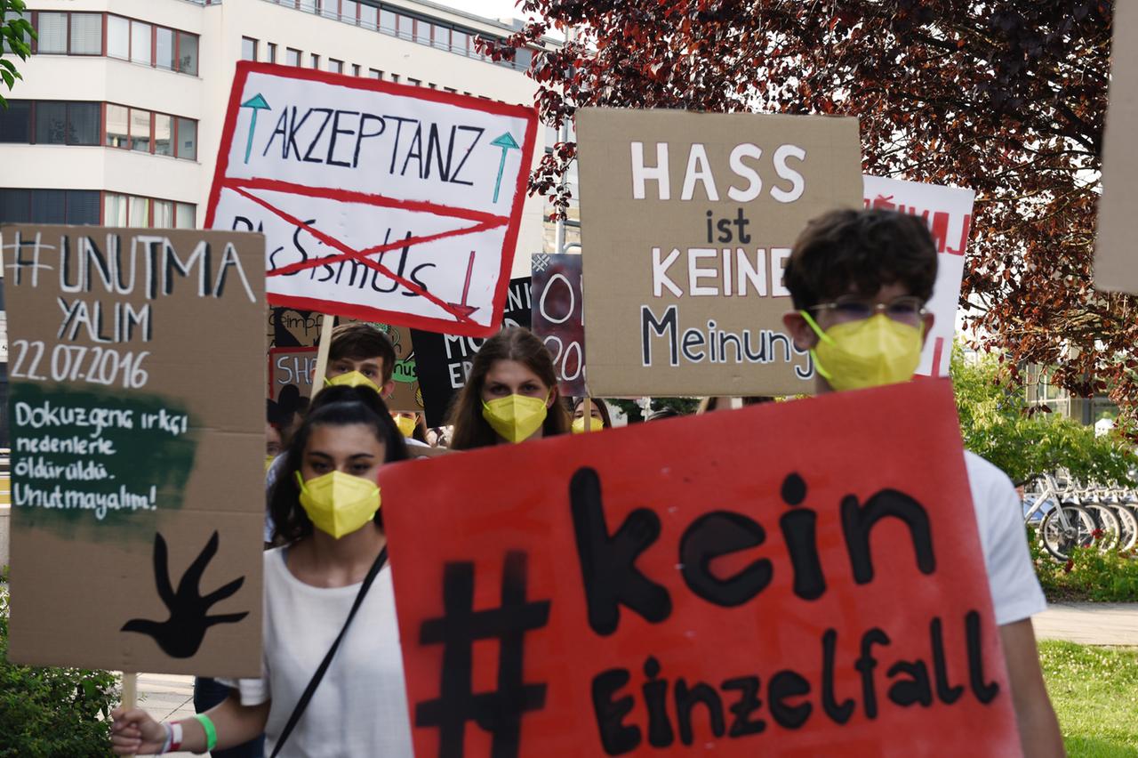 Teilnehmende des Theaterlabors der Münchner Kammerspiele im Münchner Stadtteil Neuperlach mit Protestplakaten gegen Hass und Rassismus.