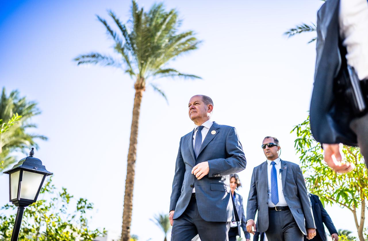 Bundeskanzler Olaf Scholz bei der UN-Weltklimakonferenz in Ägypten an einer Palme vorbei,begleitet von einem Personenschützer. Bundeskanzler Olaf Scholz bei der UN-Weltklimakonferenz in Ägypten an einer Palme vorbei,begleitet von einem Personenschützer.